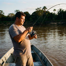 Pescador brigando com um peixe usando o Molinete Shimano Catana